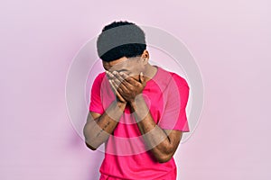 Young african american man wearing casua t shirt with sad expression covering face with hands while crying