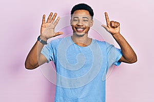 Young african american man wearing casual blue t shirt showing and pointing up with fingers number seven while smiling confident