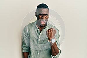 Young african american man wearing casual clothes angry and mad raising fist frustrated and furious while shouting with anger