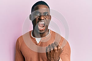 Young african american man wearing casual clothes angry and mad raising fist frustrated and furious while shouting with anger