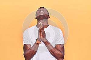 Young african american man wearing casual clothes begging and praying with hands together with hope expression on face very