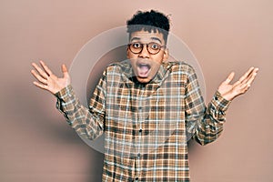 Young african american man wearing casual clothes and glasses celebrating victory with happy smile and winner expression with