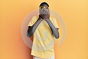 Young african american man wearing casual clothes and glasses shocked covering mouth with hands for mistake