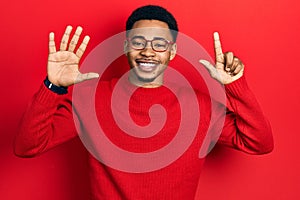 Young african american man wearing casual clothes and glasses showing and pointing up with fingers number seven while smiling