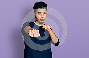 Young african american man wearing casual clothes punching fist to fight, aggressive and angry attack, threat and violence