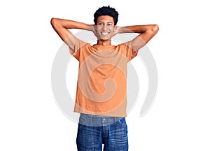 Young african american man wearing casual clothes relaxing and stretching, arms and hands behind head and neck smiling happy