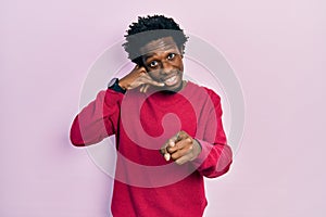 Young african american man wearing casual clothes smiling doing talking on the telephone gesture and pointing to you