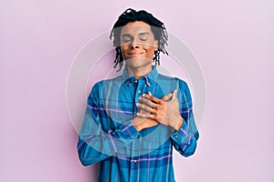 Young african american man wearing casual clothes smiling with hands on chest with closed eyes and grateful gesture on face