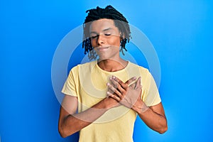 Young african american man wearing casual clothes smiling with hands on chest, eyes closed with grateful gesture on face