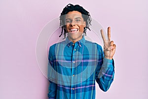 Young african american man wearing casual clothes smiling with happy face winking at the camera doing victory sign