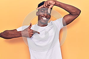 Young african american man wearing casual clothes smiling making frame with hands and fingers with happy face