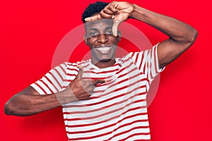 Young african american man wearing casual clothes smiling making frame with hands and fingers with happy face