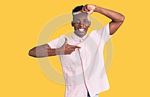 Young african american man wearing casual clothes smiling making frame with hands and fingers with happy face