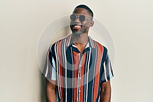 Young african american man wearing casual clothes and sunglasses with a happy and cool smile on face