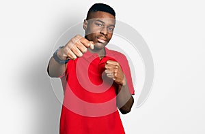 Young african american man wearing casual red t shirt punching fist to fight, aggressive and angry attack, threat and violence