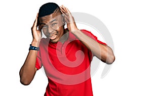 Young african american man wearing casual red t shirt trying to hear both hands on ear gesture, curious for gossip
