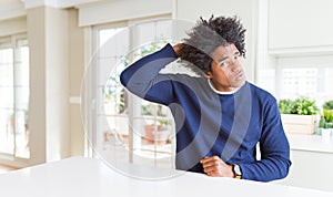 Young african american man wearing casual sweater sitting at home confuse and wondering about question