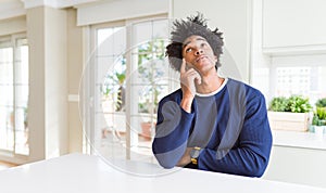 Young african american man wearing casual sweater sitting at home with hand on chin thinking about question, pensive expression