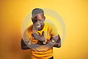 Young african american man wearing casual t-shirt standing over isolated yellow background smiling and laughing hard out loud