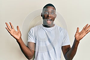 Young african american man wearing casual white t shirt celebrating victory with happy smile and winner expression with raised