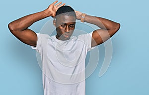 Young african american man wearing casual white t shirt doing bunny ears gesture with hands palms looking cynical and skeptical