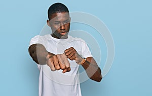 Young african american man wearing casual white t shirt punching fist to fight, aggressive and angry attack, threat and violence