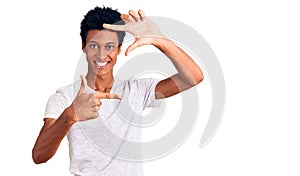 Young african american man wearing casual white t shirt smiling making frame with hands and fingers with happy face