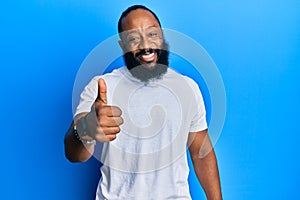 Young african american man wearing casual white tshirt doing happy thumbs up gesture with hand