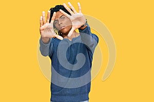 Young african american man wearing casual winter sweater doing frame using hands palms and fingers, camera perspective
