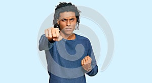 Young african american man wearing casual winter sweater punching fist to fight, aggressive and angry attack, threat and violence