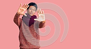 Young african american man wearing casual winter sweater and scarf doing frame using hands palms and fingers, camera perspective