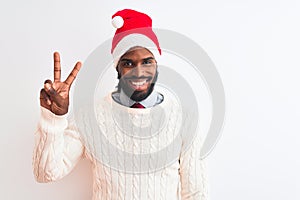 Young african american man wearing Christmas Santa hat over isolated white background smiling with happy face winking at the