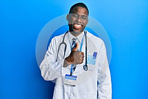 Young african american man wearing doctor uniform doing happy thumbs up gesture with hand