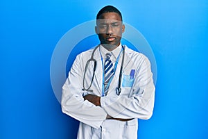 Young african american man wearing doctor uniform skeptic and nervous, disapproving expression on face with crossed arms