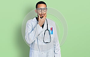 Young african american man wearing doctor uniform and stethoscope looking fascinated with disbelief, surprise and amazed