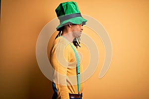 Young african american man wearing green hat celebrating saint patricks day looking to side, relax profile pose with natural face