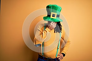 Young african american man wearing green hat celebrating saint patricks day tired rubbing nose and eyes feeling fatigue and