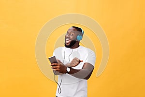 Young African American man wearing headphone and enjoy music over yellow gold Background