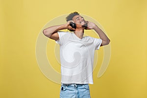 Young African American man wearing headphone and enjoy music over yellow gold Background photo