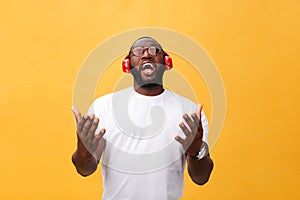 Young African American man wearing headphone and enjoy music over yellow gold Background