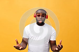 Young African American man wearing headphone and enjoy music over yellow gold Background