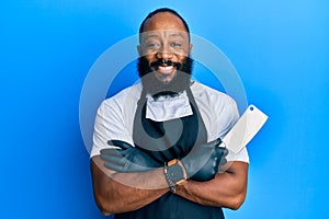 Young african american man wearing professional apron holding knife smiling with a happy and cool smile on face