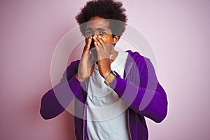 Young african american man wearing purple sweatshirt standing over isolated pink background Shouting angry out loud with hands