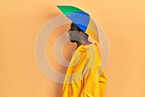 Young african american man wearing yellow raincoat looking to side, relax profile pose with natural face and confident smile