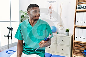 Young african american man working at pain recovery clinic looking to side, relax profile pose with natural face and confident