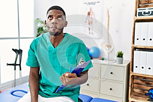 Young african american man working at pain recovery clinic making fish face with lips, crazy and comical gesture