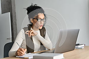 Young African American mixed race girl sitting at desk with pc indoors.