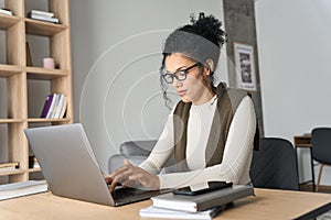 Young African American mixed race girl sitting at desk typing on pc indoors.