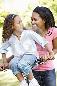 Young African American Mother And Daughter Cycling In Park