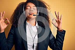 Young african american operator woman with afro hair wearing headset over yellow background relax and smiling with eyes closed